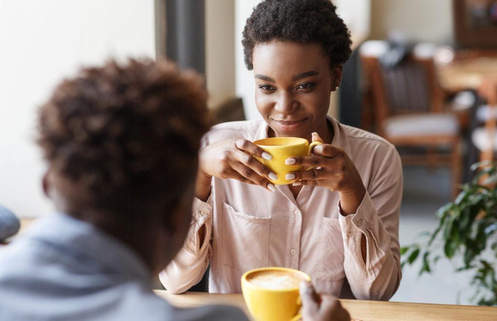 Young black couple drinking coffee together on date at cozy cafe